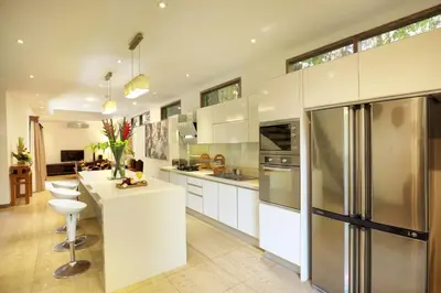a kitchen with white cabinets and stainless steel appliances at Villa The Hotman Paris II Seminyak in Seminyak