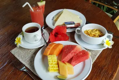 a table with two plates of food and a cup of coffee at Hotel Puri Bambu in Jimbaran