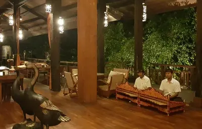 two men sitting in a restaurant with a swan on the floor at Hotel Puri Bambu in Jimbaran