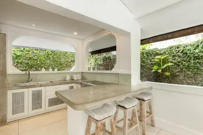 a kitchen with a counter with stools and two windows at Esha Villa Drupadi Seminyak in Seminyak