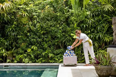 a woman standing next to a basket of balls next to a pool at Esha Villa Drupadi Seminyak in Seminyak