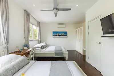 a bedroom with two beds and a flat screen tv at Esha Villa Drupadi Seminyak in Seminyak