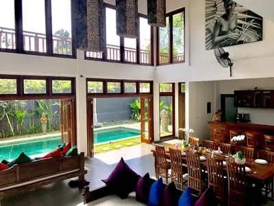a living room with a table and a swimming pool at Villa Khaleesi in Seminyak