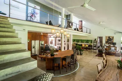 a dining room and living room with a table and stairs at Kamehameha Luxury Villa in Seminyak