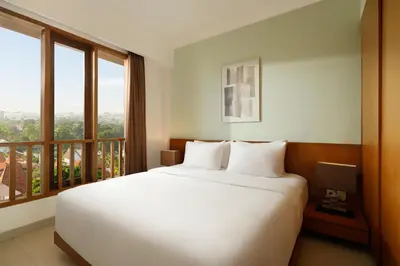 a bedroom with a large white bed and a balcony at Sara Residence by Nakula in Legian