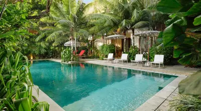 a swimming pool with white chairs and palm trees at Sara Residence by Nakula in Legian
