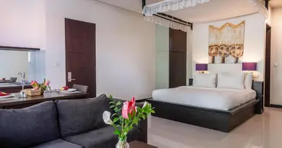 a hotel room with a bed and a couch at Swiss-Belcourt Sunset in Seminyak