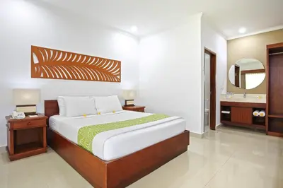 a bedroom with a large bed and a mirror at Dewi Sri Hotel in Legian