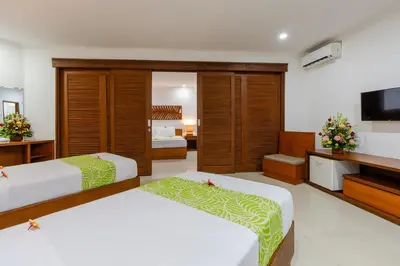 a hotel room with two beds and a flat screen tv at Dewi Sri Hotel in Legian