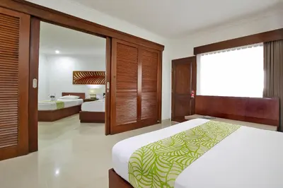 a bedroom with two beds and a large window at Dewi Sri Hotel in Legian