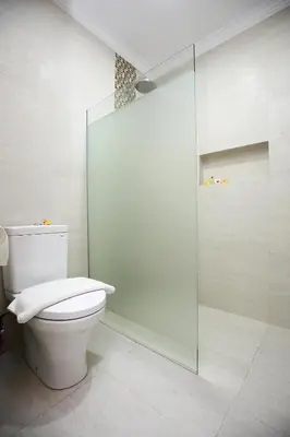 a bathroom with a toilet and a glass shower at Dewi Sri Hotel in Legian