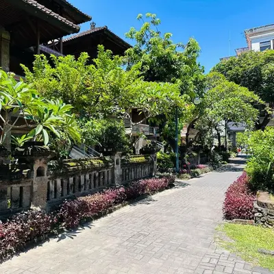 a walkway in front of a house with trees and flowers at Melasti Kuta Beach Hotel & Spa in Kuta