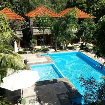 a swimming pool with an umbrella next to a house at Melasti Kuta Beach Hotel & Spa in Kuta