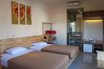 a hotel room with two beds and a television at Hotel Karthi Kuta in Kuta