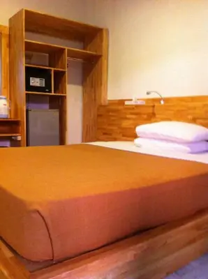 a bedroom with a large bed with an orange blanket at Hotel Karthi Kuta in Kuta