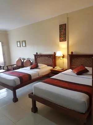 a hotel room with three beds in a room at Melasti Beach Resort & Spa Legian in Legian