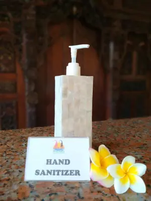a bottle of hand sanitizer and flowers on a counter at Melasti Beach Resort & Spa Legian in Legian