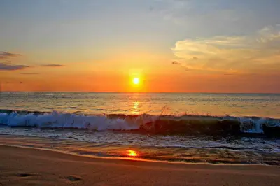 a sunset on the beach with the ocean at Melasti Beach Resort & Spa Legian in Legian