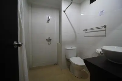 a white bathroom with a toilet and a sink at Bakung Sari Resort in Kuta