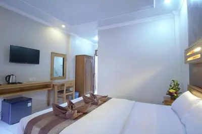 a bedroom with a large bed with a tv on the wall at Bakung Sari Resort in Kuta