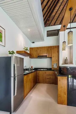 a kitchen with wooden cabinets and a stainless steel refrigerator at Pradha Villas Seminyak in Seminyak