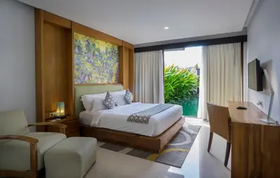 a bedroom with a bed and a desk and a television at Pradha Villas Seminyak in Seminyak