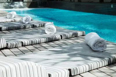 a swimming pool with chaise lounges next to the water at Downtown Villas in Seminyak