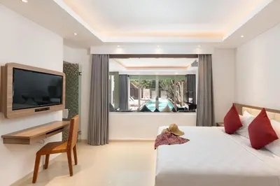 a bedroom with a bed and a television and a table at Downtown Villas in Seminyak