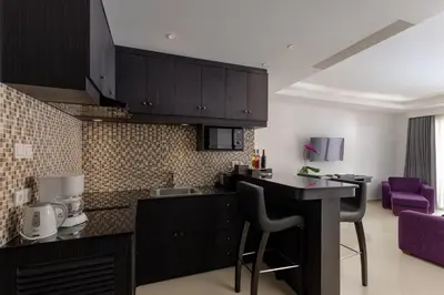 a kitchen with black cabinets and purple chairs at Downtown Villas in Seminyak