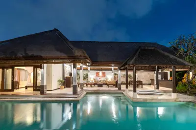 a villa with a swimming pool at night at The Maya Seminyak Villas in Seminyak