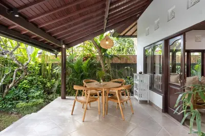 a patio with a wooden table and chairs at Twist and Shout Villa in Seminyak