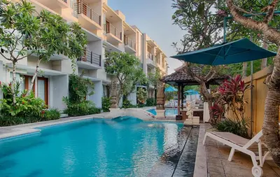a swimming pool with a umbrella and chairs and a hotel at Baleka Resort & Spa in Legian