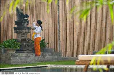 a woman standing next to a fountain talking on a cell phone at 3BR Villa Rabu - Minggu Villas Seminyak in Seminyak