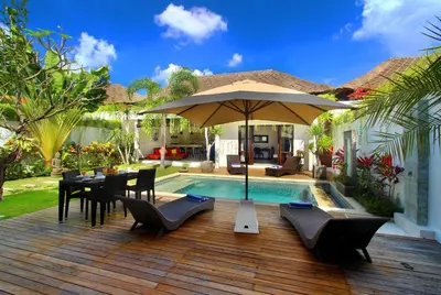 a patio with a table and an umbrella next to a pool at Villa Calypso by Optimum Bali Villas in Seminyak
