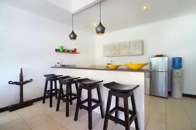 a kitchen with a bar with stools and a refrigerator at Villa Calypso by Optimum Bali Villas in Seminyak