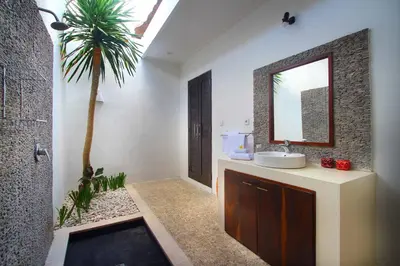 a bathroom with a sink and a mirror and a palm tree at Villa Calypso by Optimum Bali Villas in Seminyak
