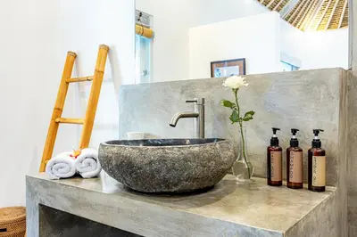 a bathroom with a stone sink and some bottles at Renovated Villa Gladak, 200m to Oberoi Seminyak in Seminyak