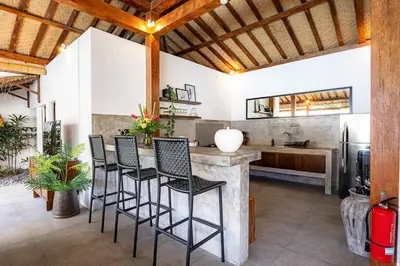 a kitchen with a bar with chairs and a sink at Renovated Villa Gladak, 200m to Oberoi Seminyak in Seminyak
