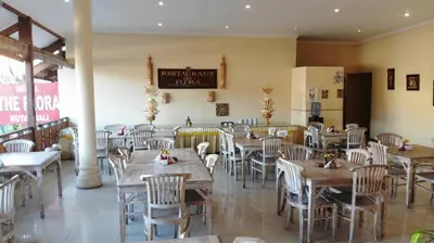 a restaurant with wooden tables and chairs in a room at The Flora Kuta Bali in Kuta
