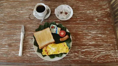 a plate of breakfast food on a table with a cup of coffee at The Flora Kuta Bali in Kuta