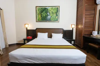 a bedroom with a bed and a painting on the wall at The Flora Kuta Bali in Kuta