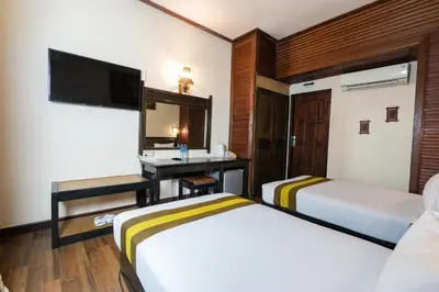 a hotel room with two beds and a desk at The Flora Kuta Bali in Kuta