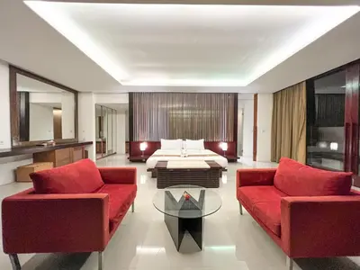 a living room with red furniture and a bed at The Wangsa Benoa in Nusa Dua