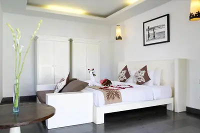 a white bedroom with a white bed and a table at Nunia Boutique Villa in Seminyak