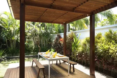 a table and chairs on a wooden deck with a pergola at Nunia Boutique Villa in Seminyak