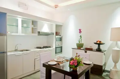a kitchen with white cabinets and a table with flowers on it at Nunia Boutique Villa in Seminyak
