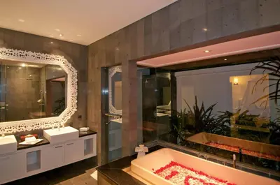 a bathroom with a tub and a large mirror at Nunia Boutique Villa in Seminyak