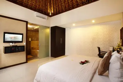 a bedroom with a white bed and a television at Putu Bali Villa & Spa in Seminyak