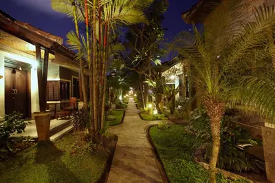 a garden with palm trees in a resort at night at Putu Bali Villa & Spa in Seminyak