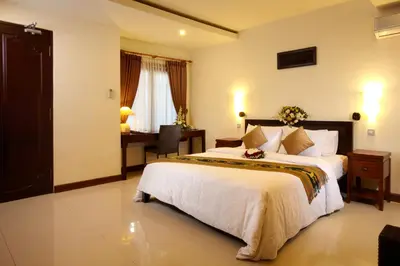 a bedroom with a large bed and a desk at Putu Bali Villa & Spa in Seminyak